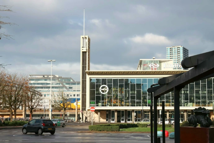 Modern building with a tall spire in a city.